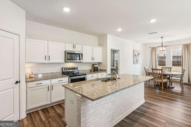 kitchen featuring white cabinetry, a center island with sink, stainless steel appliances, decorative light fixtures, and sink