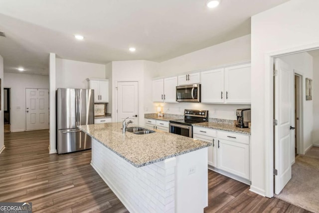 kitchen with a center island with sink, sink, white cabinetry, stainless steel appliances, and light stone counters