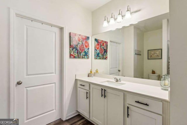 bathroom with toilet, vanity, and wood-type flooring