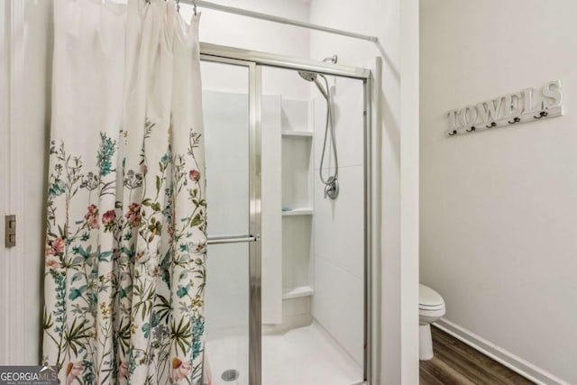 bathroom featuring hardwood / wood-style floors, toilet, and a shower with door