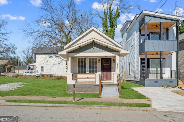 view of front of property with covered porch, a front lawn, a balcony, and ceiling fan