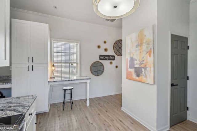 kitchen with light stone counters, white cabinetry, and ornamental molding