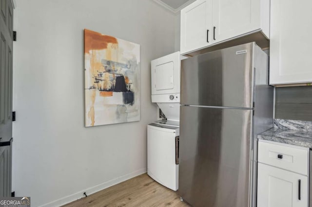 clothes washing area featuring stacked washer and dryer, ornamental molding, and light hardwood / wood-style floors