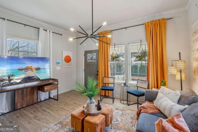 living room with crown molding, light hardwood / wood-style flooring, plenty of natural light, and a notable chandelier