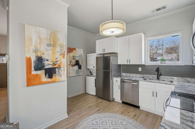 kitchen with white cabinetry, stacked washer / drying machine, stainless steel appliances, crown molding, and sink