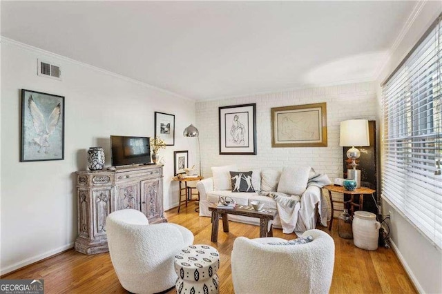 living room featuring light hardwood / wood-style floors, brick wall, and crown molding