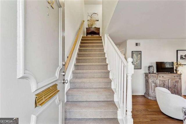 staircase featuring hardwood / wood-style flooring and crown molding