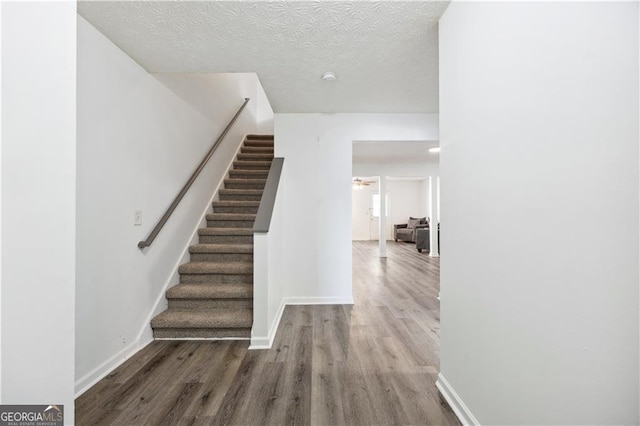 staircase featuring a textured ceiling and wood-type flooring