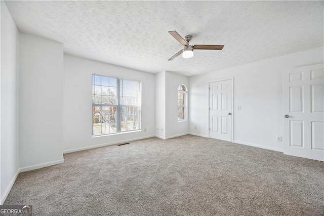 carpeted spare room with ceiling fan and a textured ceiling