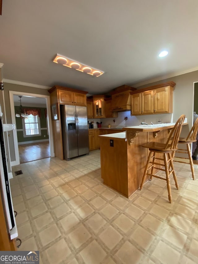 kitchen with crown molding, stainless steel fridge, a breakfast bar area, custom exhaust hood, and kitchen peninsula