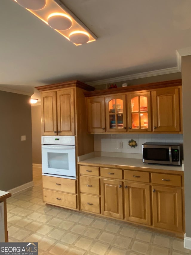 kitchen with crown molding, oven, and backsplash