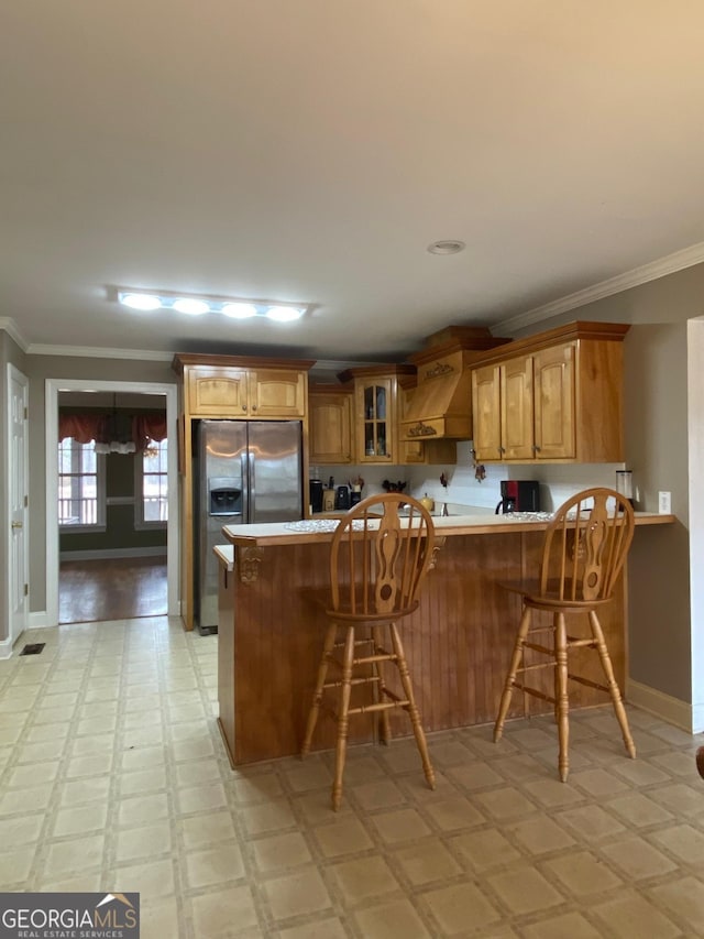 kitchen featuring crown molding, a kitchen breakfast bar, and stainless steel refrigerator with ice dispenser