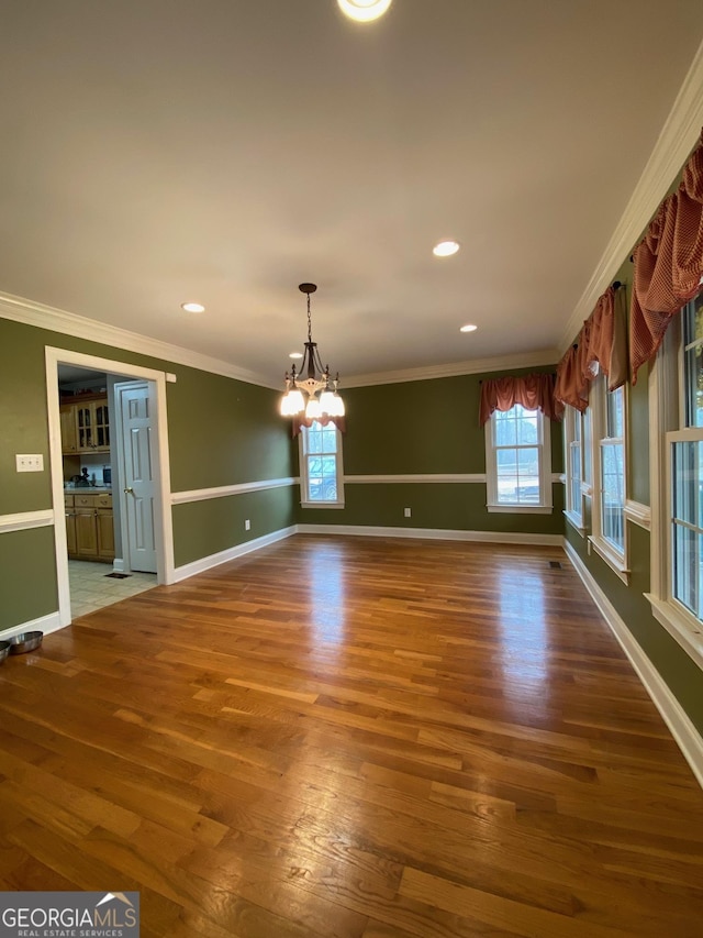 interior space with an inviting chandelier, crown molding, and hardwood / wood-style flooring