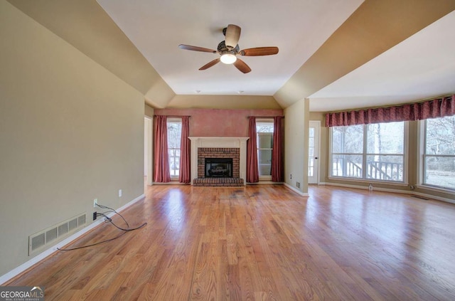 unfurnished living room with ceiling fan, light wood-type flooring, and a brick fireplace