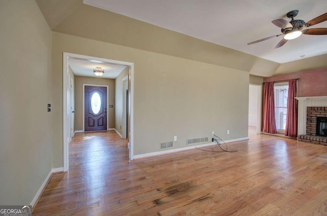 unfurnished living room featuring a brick fireplace, plenty of natural light, and light wood-type flooring