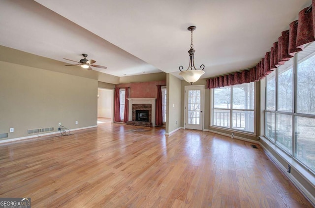 unfurnished living room featuring ceiling fan, light hardwood / wood-style flooring, and a brick fireplace