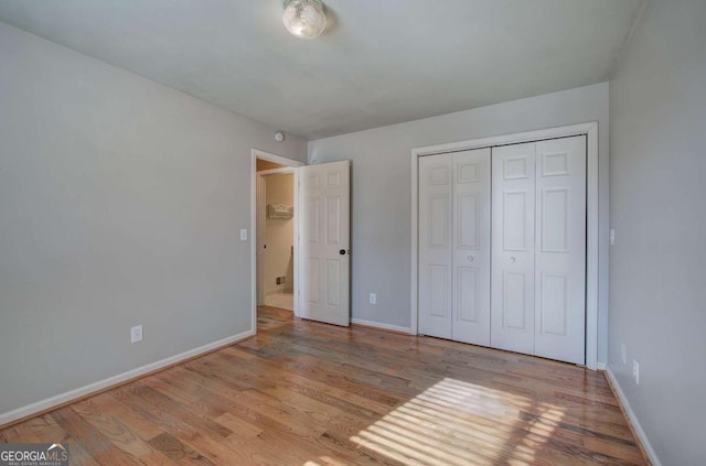 unfurnished bedroom with light wood-type flooring and a closet