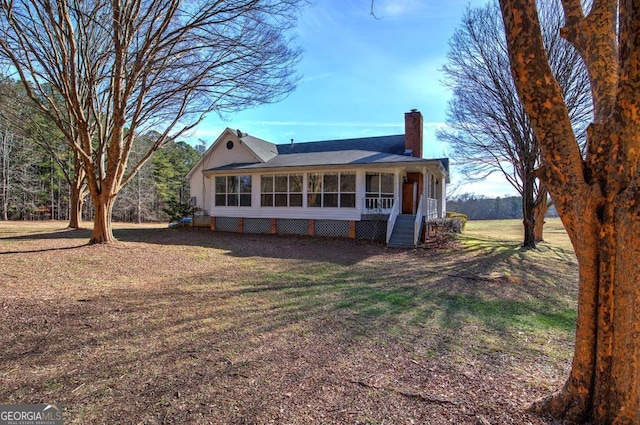 rear view of house with a yard and a sunroom