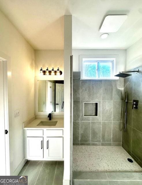 bathroom with tiled shower and vanity