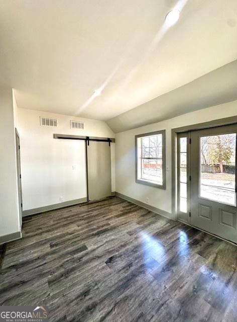 entryway with vaulted ceiling, a barn door, and dark hardwood / wood-style floors