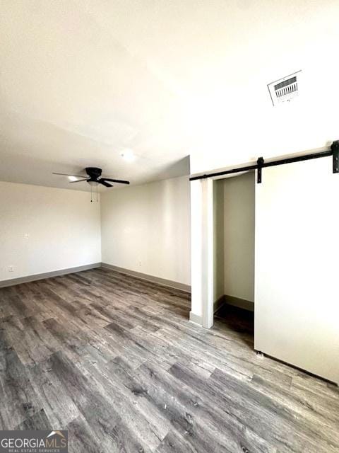 interior space featuring ceiling fan, a closet, a barn door, and wood-type flooring