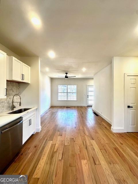 kitchen featuring backsplash, dishwasher, light hardwood / wood-style floors, sink, and white cabinets