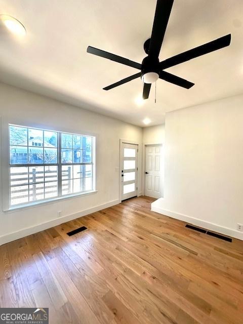 empty room with ceiling fan and light hardwood / wood-style flooring