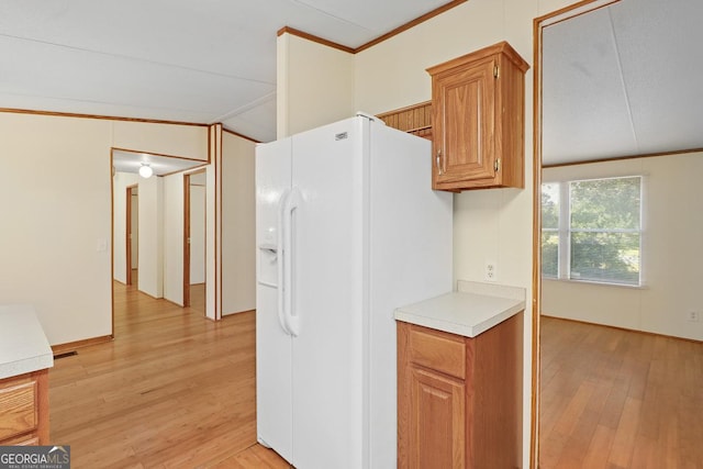 kitchen featuring white fridge with ice dispenser, light hardwood / wood-style flooring, crown molding, and vaulted ceiling