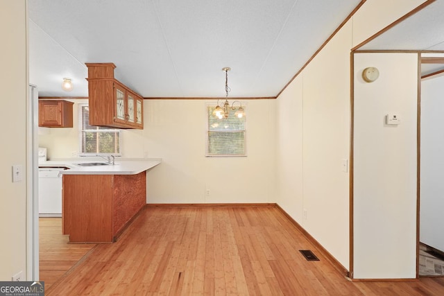 kitchen with light hardwood / wood-style floors, pendant lighting, kitchen peninsula, sink, and white dishwasher