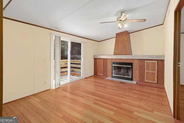 unfurnished living room with light hardwood / wood-style floors, ornamental molding, ceiling fan, and a fireplace