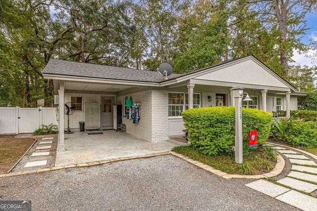 ranch-style house with a front lawn, a porch, and a carport