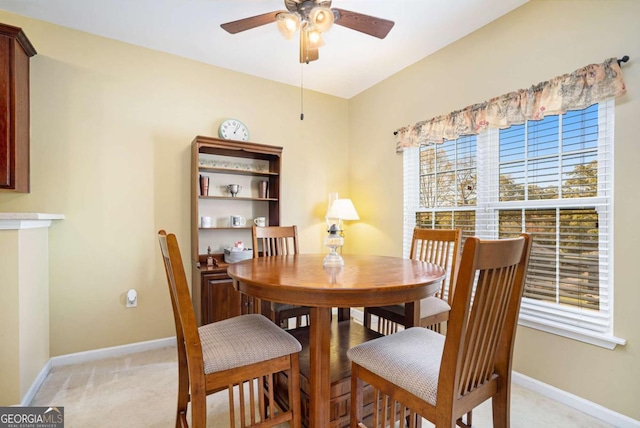 dining space with light carpet and ceiling fan