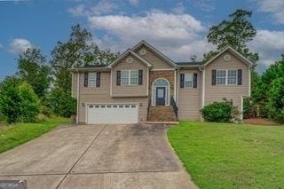 raised ranch featuring a front lawn and a garage