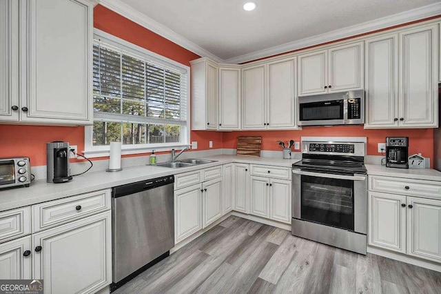 kitchen with sink, crown molding, stainless steel appliances, and light hardwood / wood-style flooring