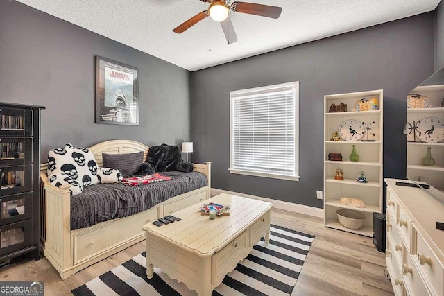 bedroom with a textured ceiling, ceiling fan, and light hardwood / wood-style floors