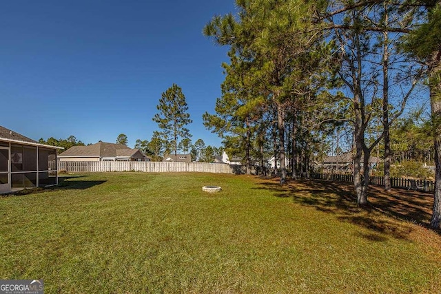 view of yard featuring a sunroom and an outdoor fire pit