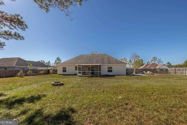 rear view of property with a lawn, a fire pit, and a sunroom