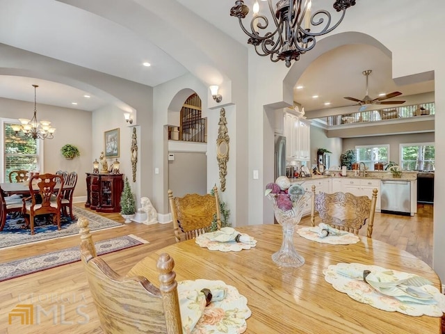 dining area featuring ceiling fan with notable chandelier and light hardwood / wood-style floors