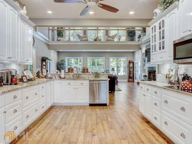 kitchen featuring white cabinetry, stainless steel appliances, decorative backsplash, kitchen peninsula, and light stone counters