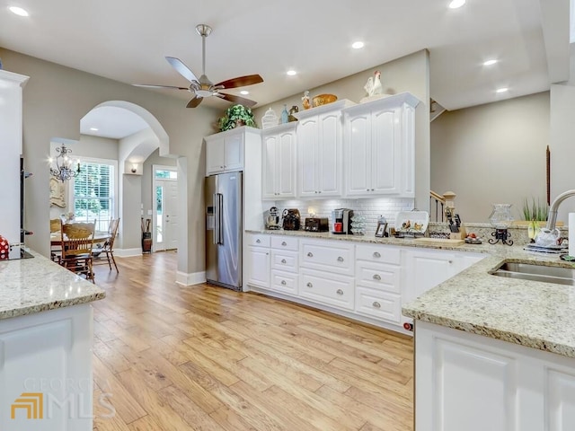 kitchen with backsplash, high end refrigerator, sink, white cabinetry, and light stone countertops