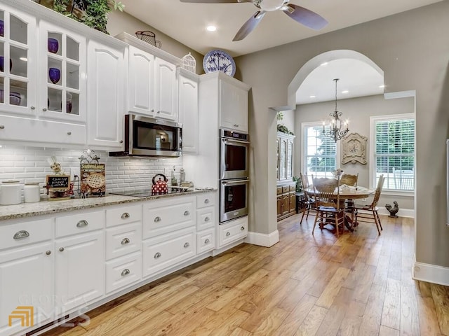 kitchen featuring tasteful backsplash, white cabinets, appliances with stainless steel finishes, and ceiling fan with notable chandelier