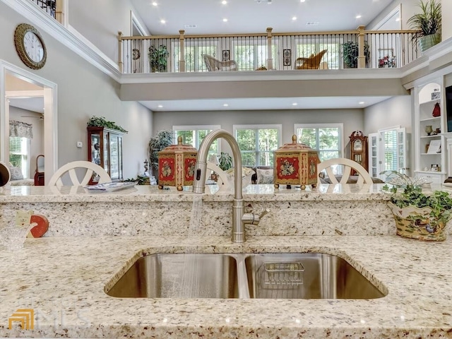 kitchen featuring a high ceiling, light stone counters, and sink