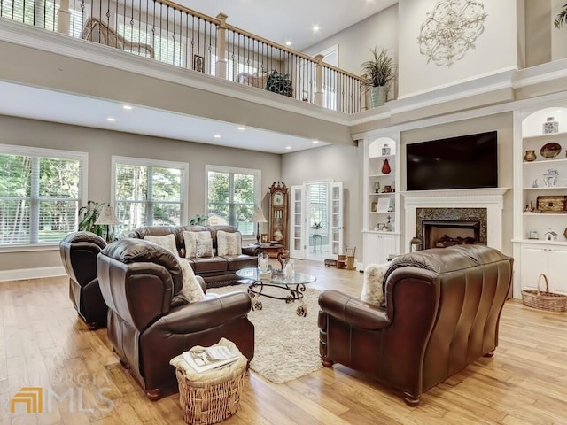 living room featuring light hardwood / wood-style floors, a high ceiling, and built in shelves