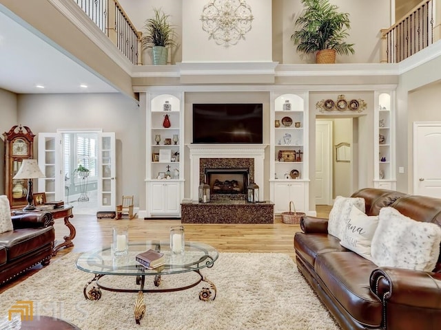 living room featuring built in features, a fireplace, and a high ceiling