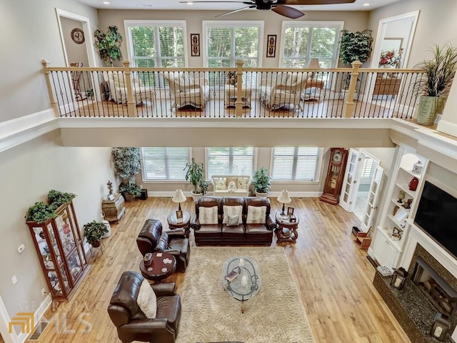 living room with ceiling fan, a fireplace, light wood-type flooring, and a healthy amount of sunlight