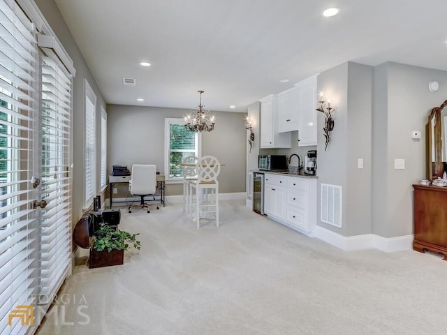 kitchen with decorative light fixtures, light colored carpet, and white cabinets