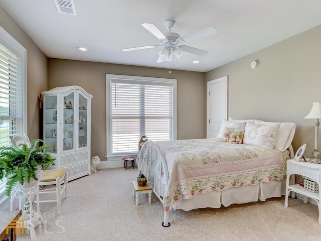 bedroom featuring ceiling fan, light carpet, and multiple windows