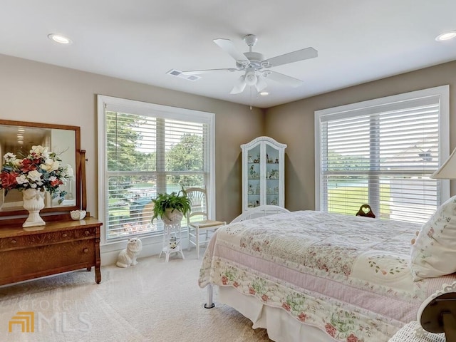 carpeted bedroom with ceiling fan and multiple windows