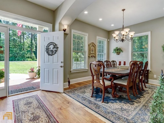 dining room with plenty of natural light, wood-type flooring, and an inviting chandelier