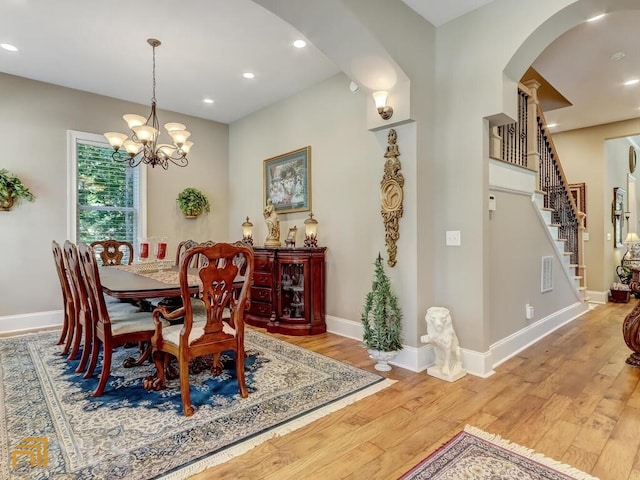 dining area with light hardwood / wood-style floors and a notable chandelier